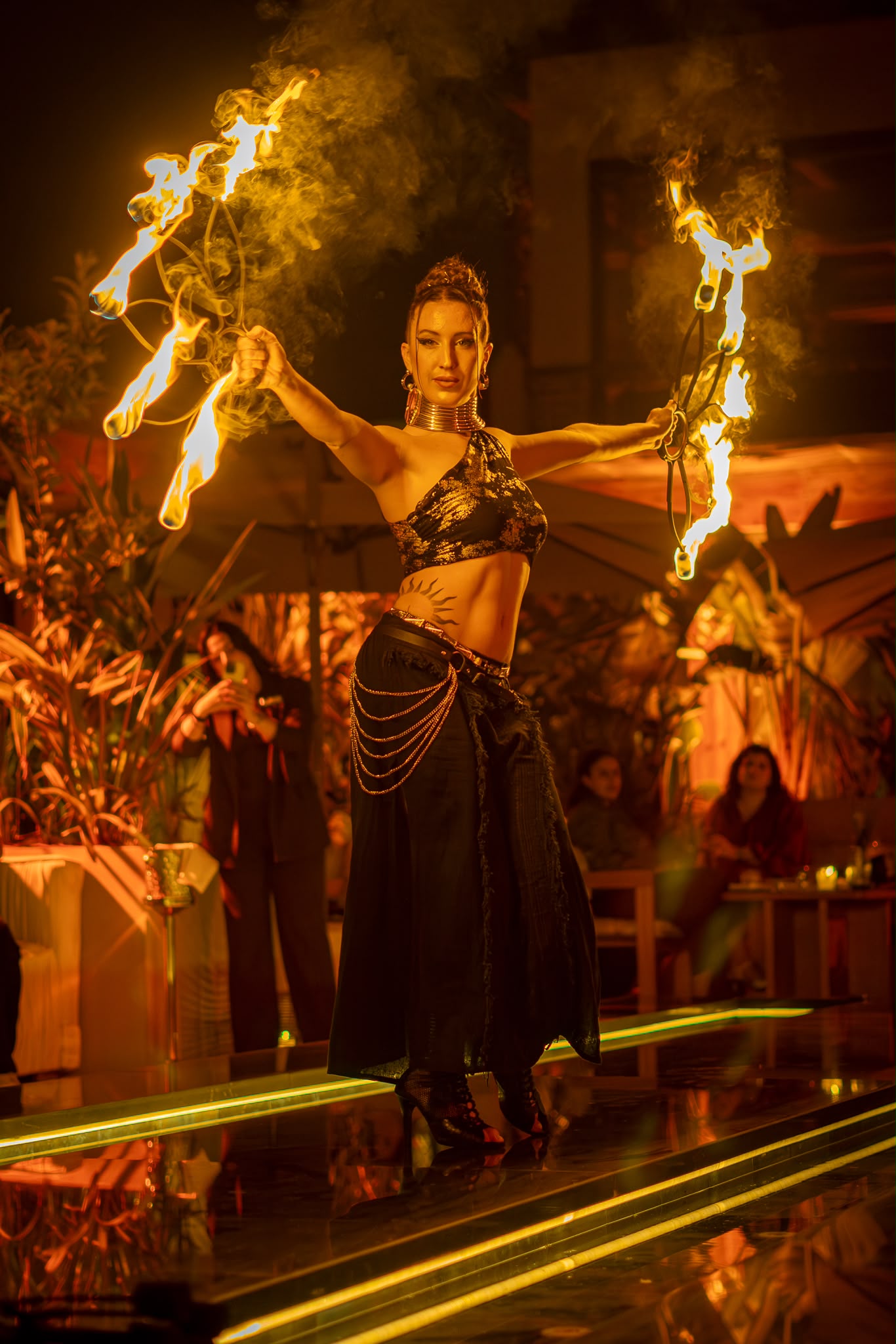 Sereia holding fire palms during a luxury evening performance
